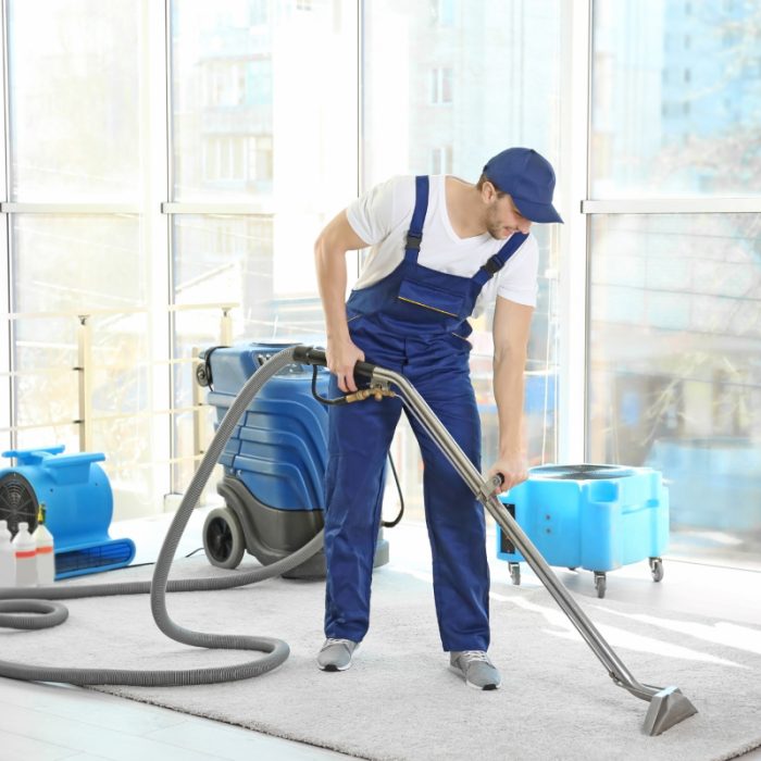 Nettoyeur professionnel passant l'aspirateur dans un salon lumineux et spacieux.